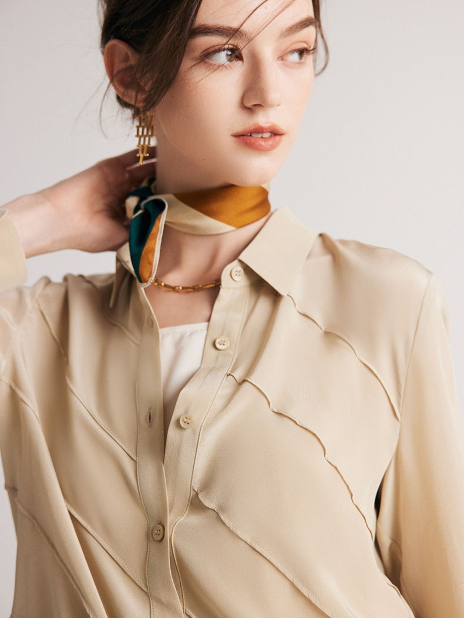 A woman wearing an off-white structured striped silk blouse with a classic collar, paired with a brown skirt.
