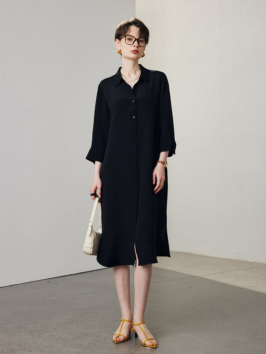 A woman with short hair wearing a lose dress shirt in black.