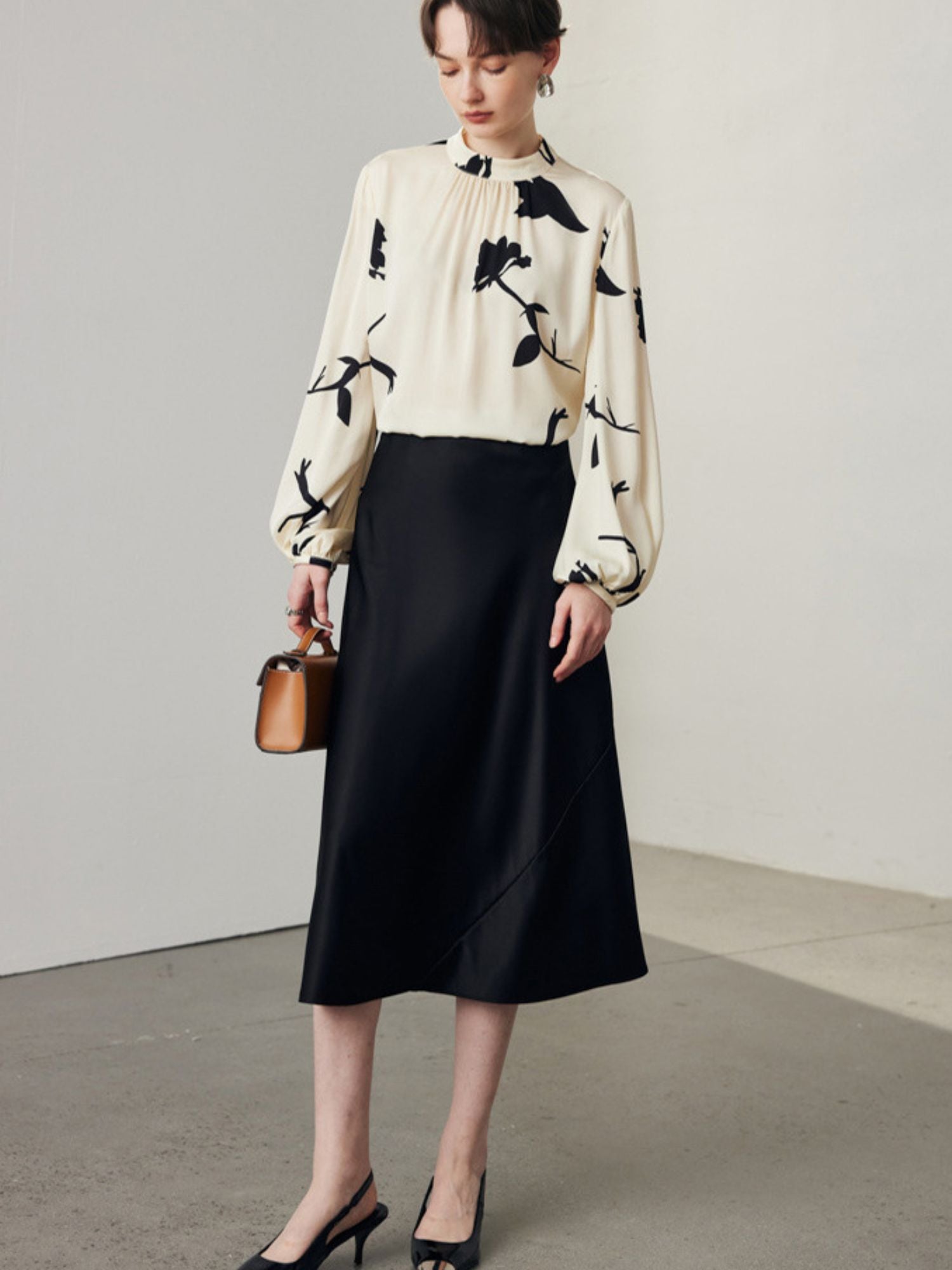A flared midi skirt in black color, made from a blend of silk and spandex, with an elastic waistband.