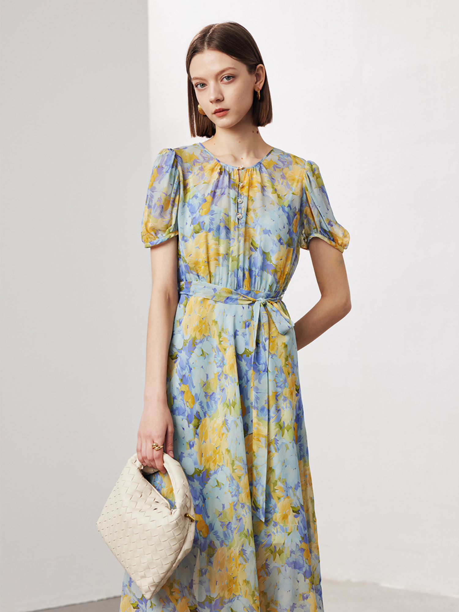 A woman wearing a floral dress holding a bag.