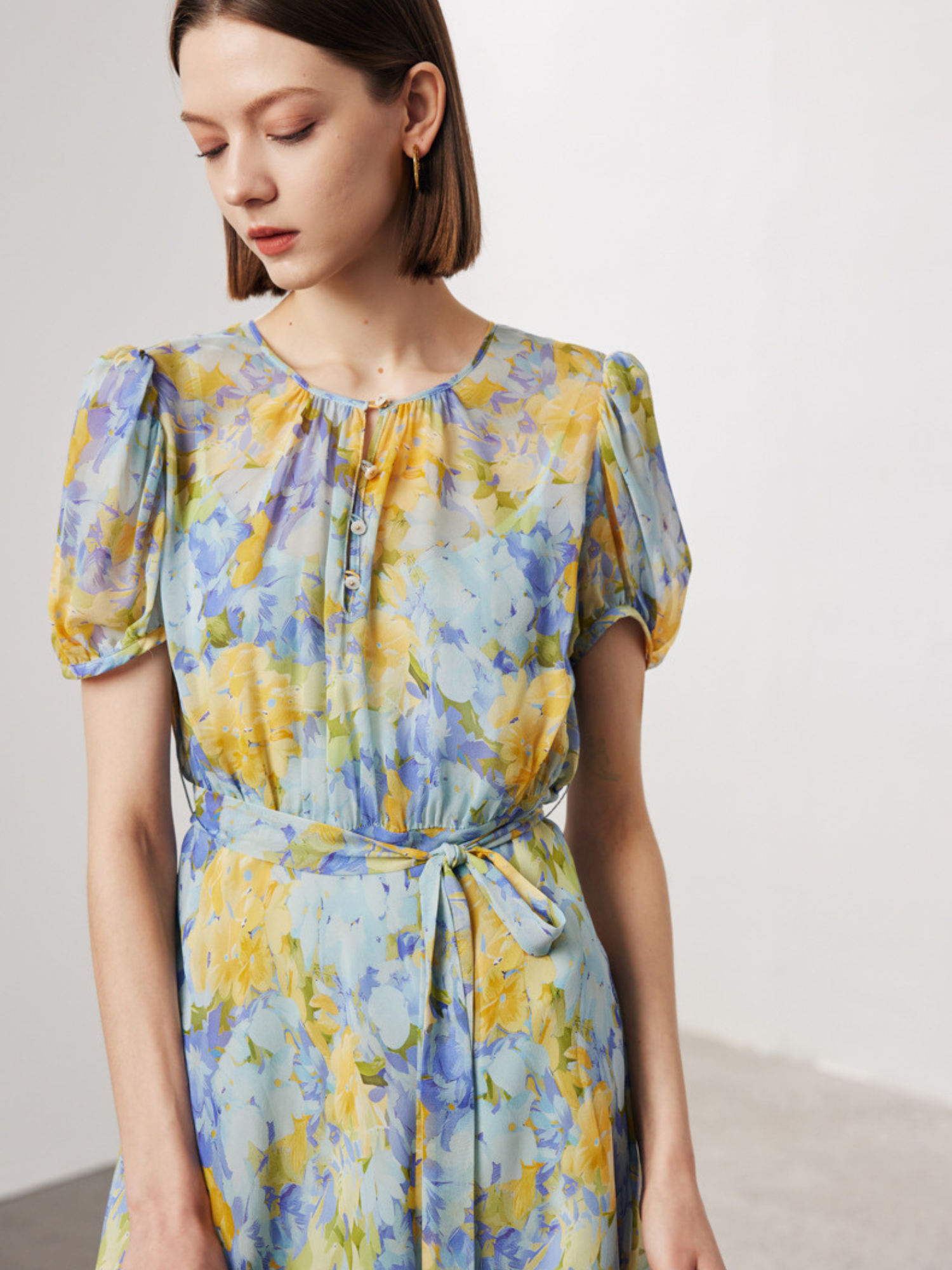 A woman wearing a floral dress looking down.