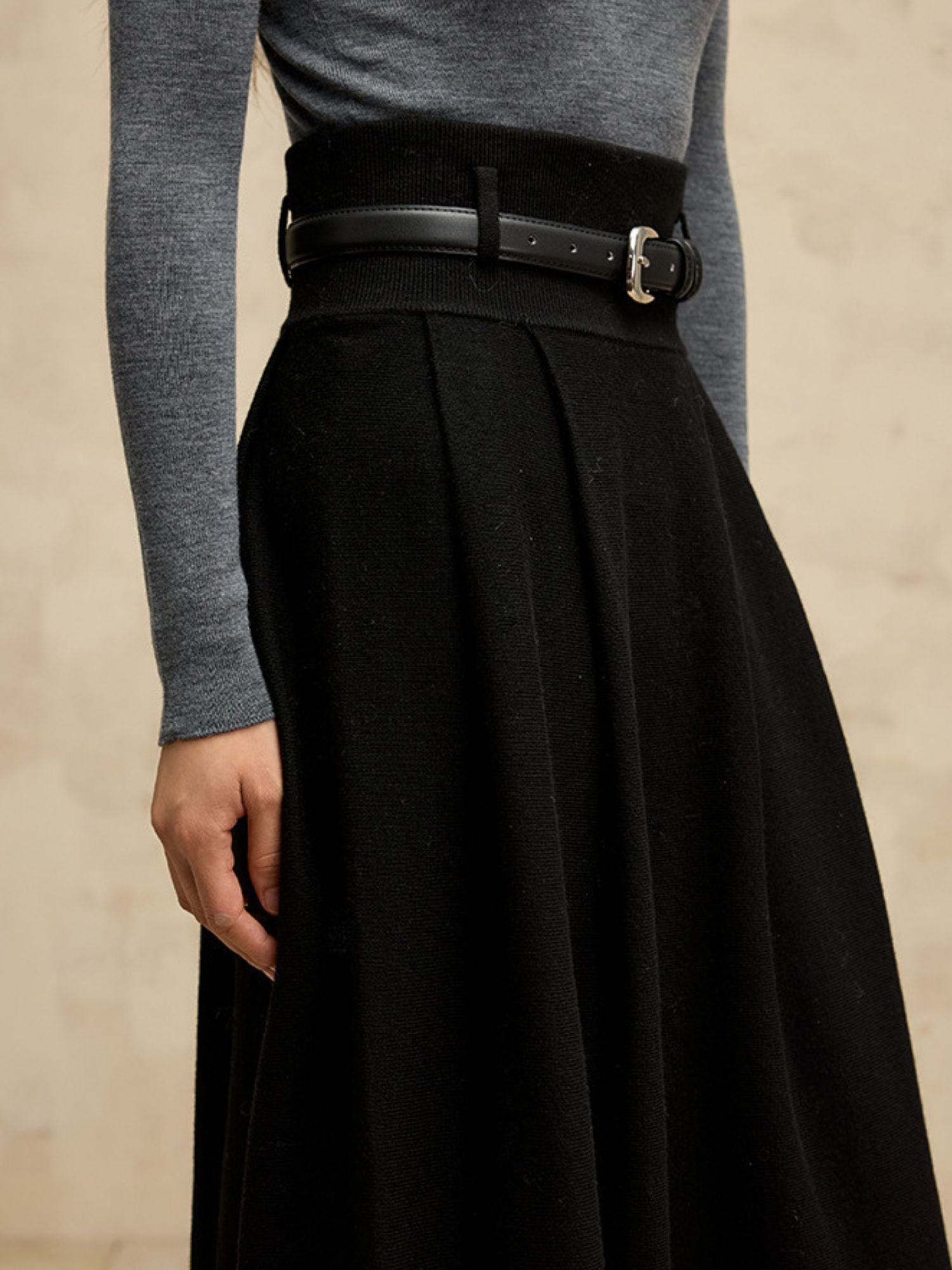 Close up of a black skirt with a black leather belt.