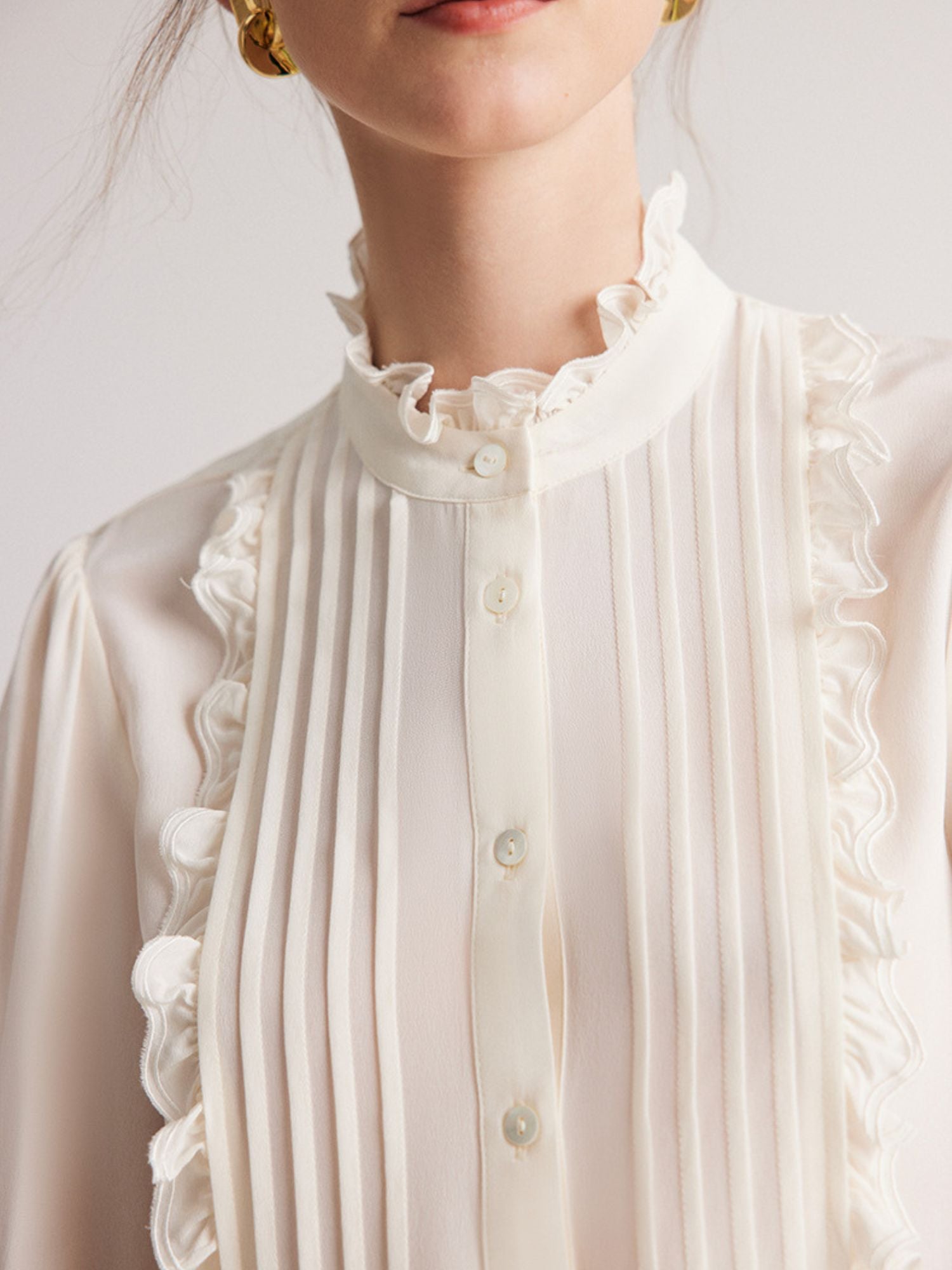 Close up of a woman wearing a ruffled blouse.