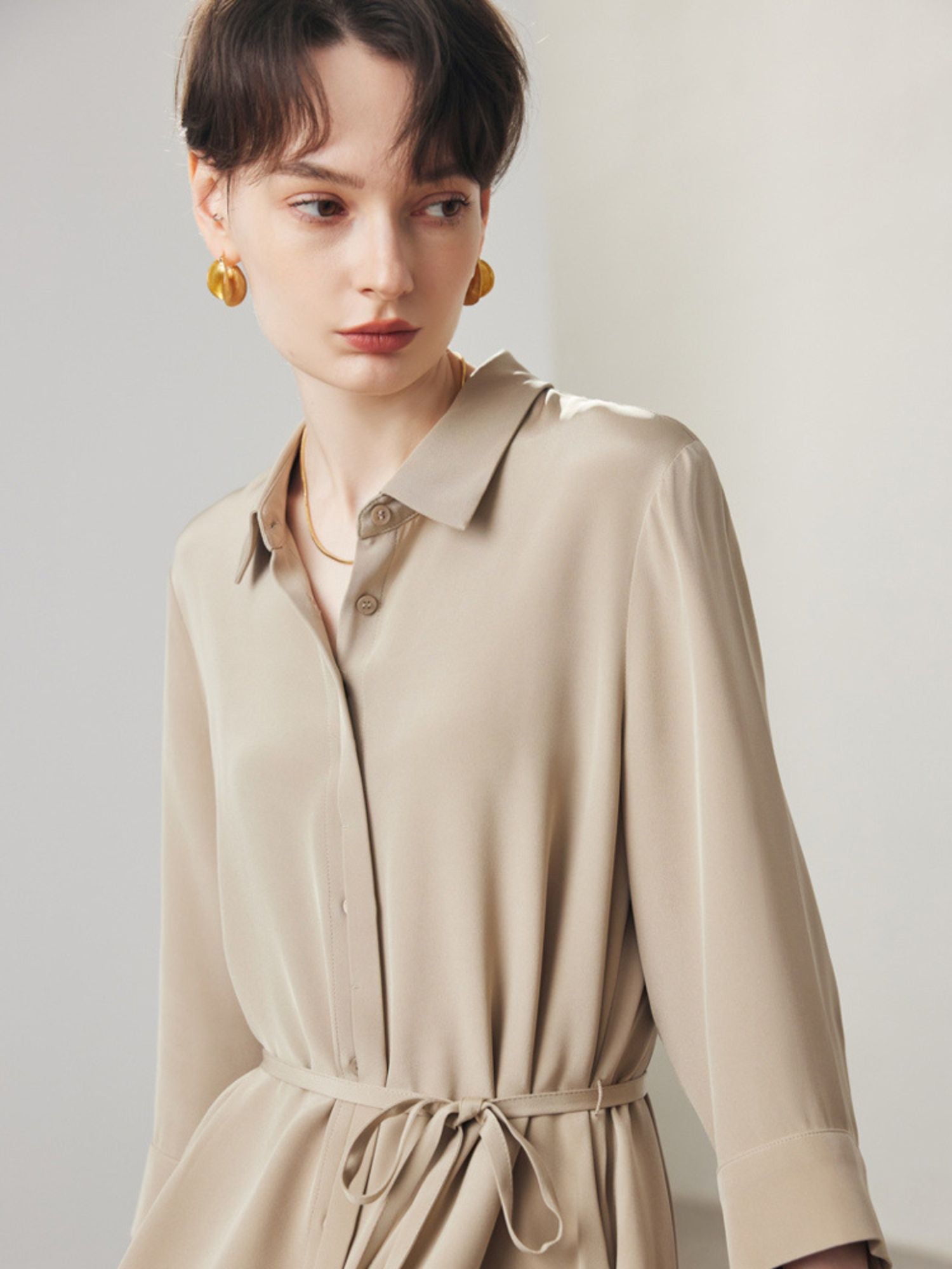 A woman wearing a beige shirt dress.
