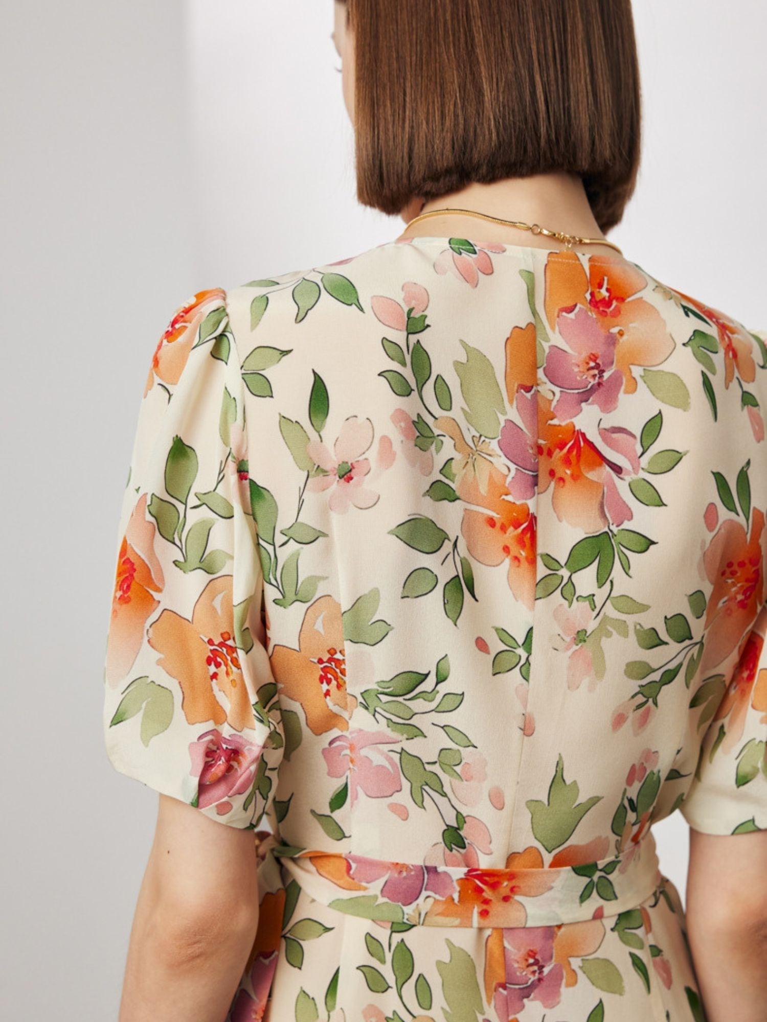 BAck view of A woman wearing a wrap around floral dress.