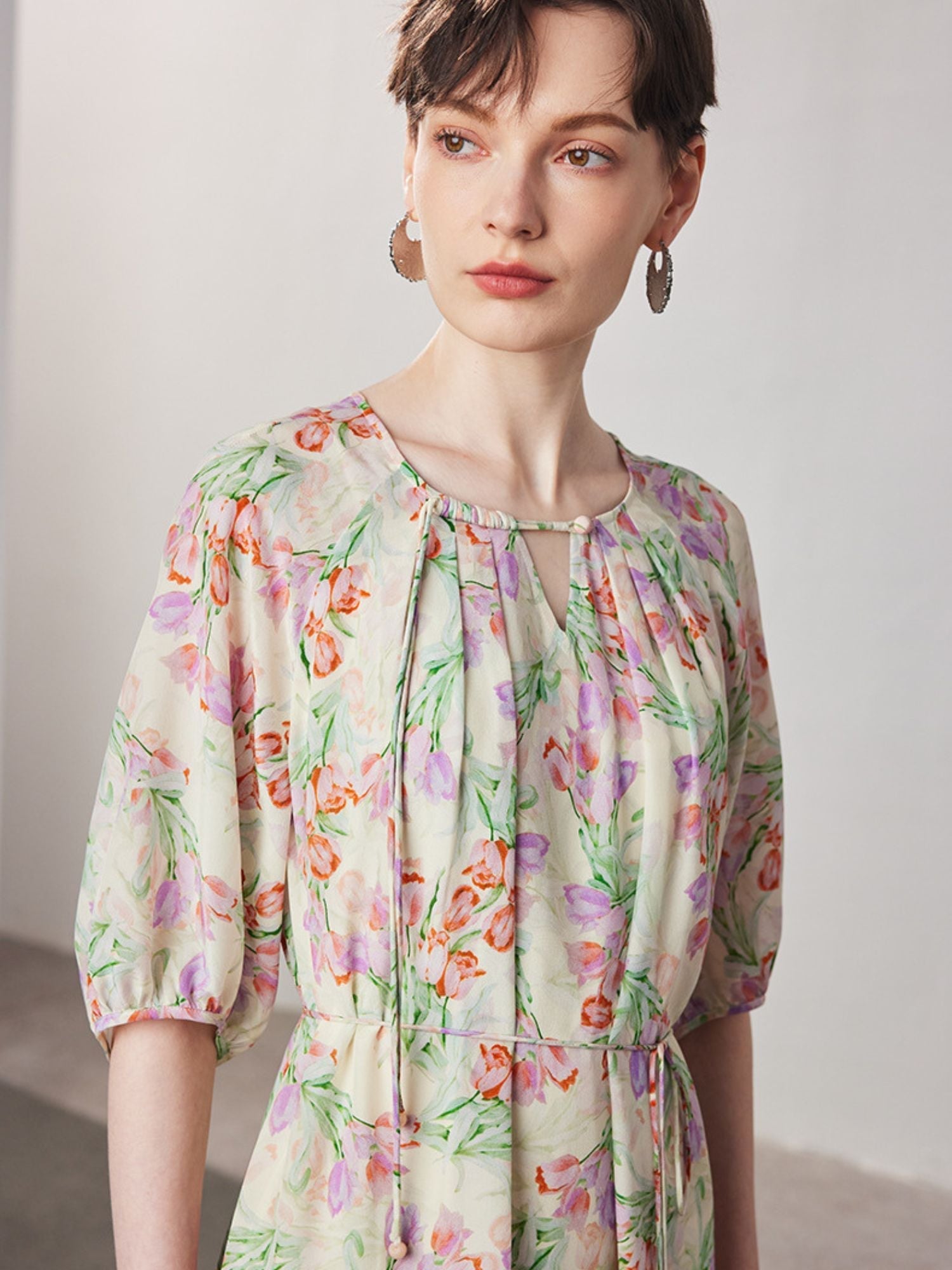 A woman with short hair wearing a floral dress.