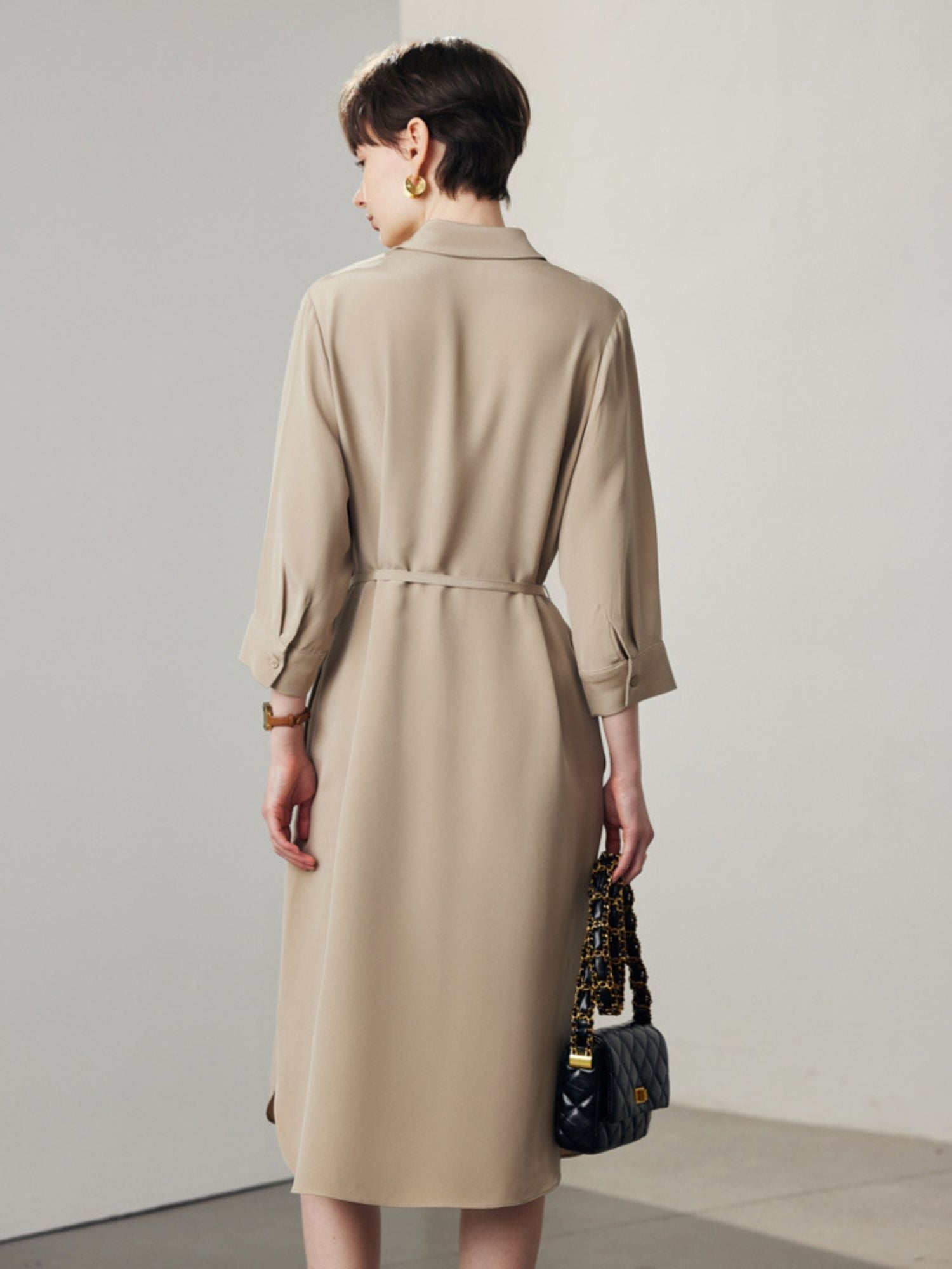 Back view of A woman wearing a beige shirt dress.