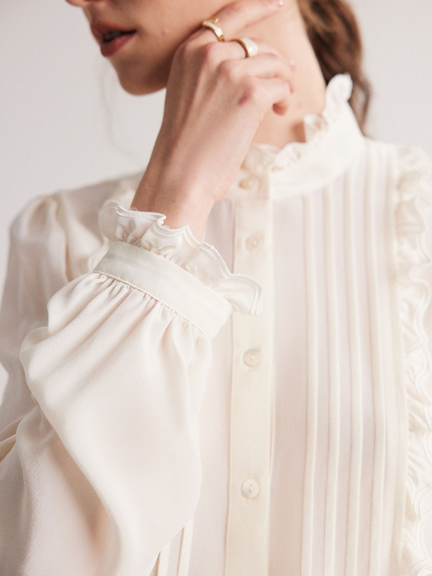 Close up of the cuff detail of a rufled white blouse.